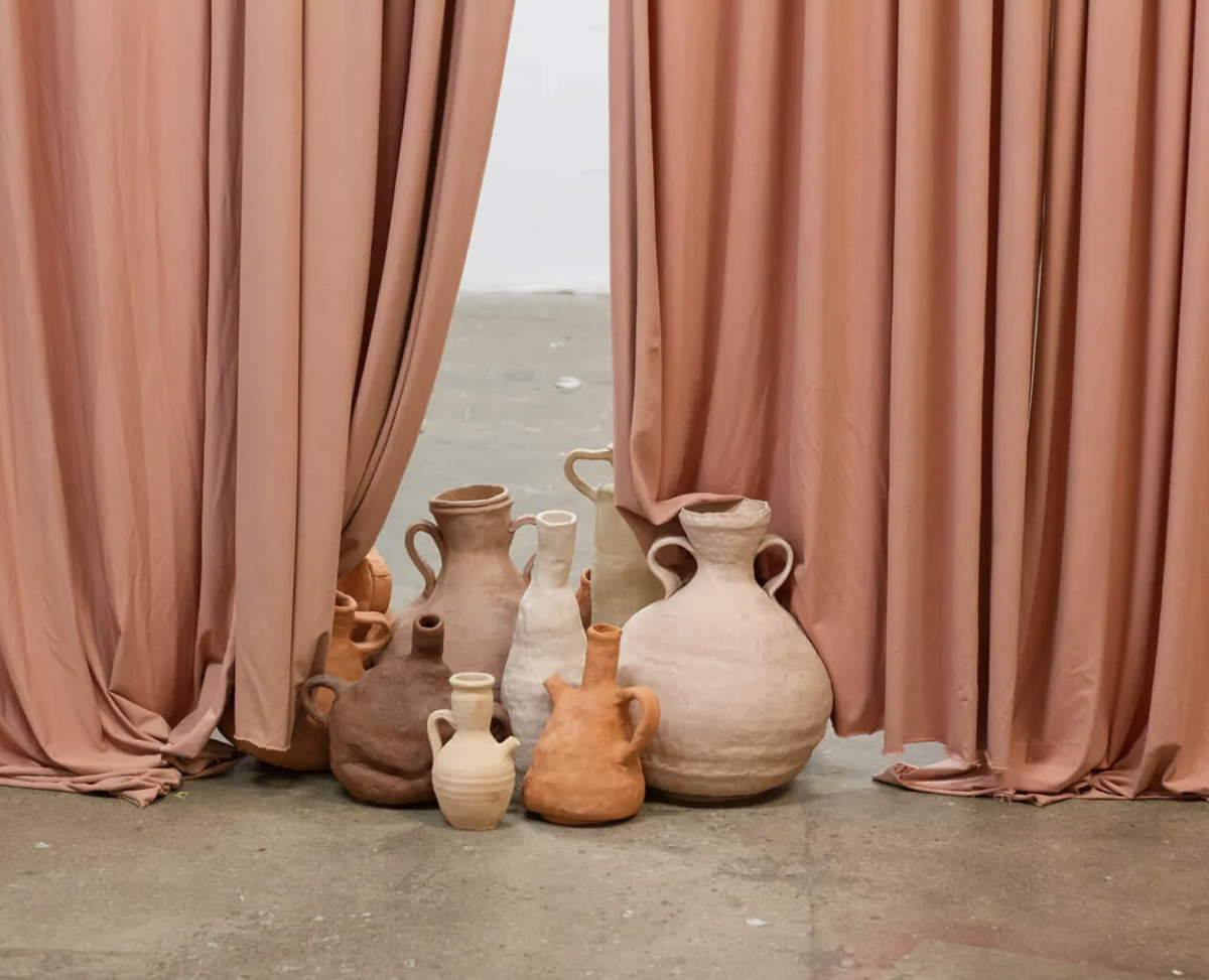 Curatorial installation with vessels and draped fabric